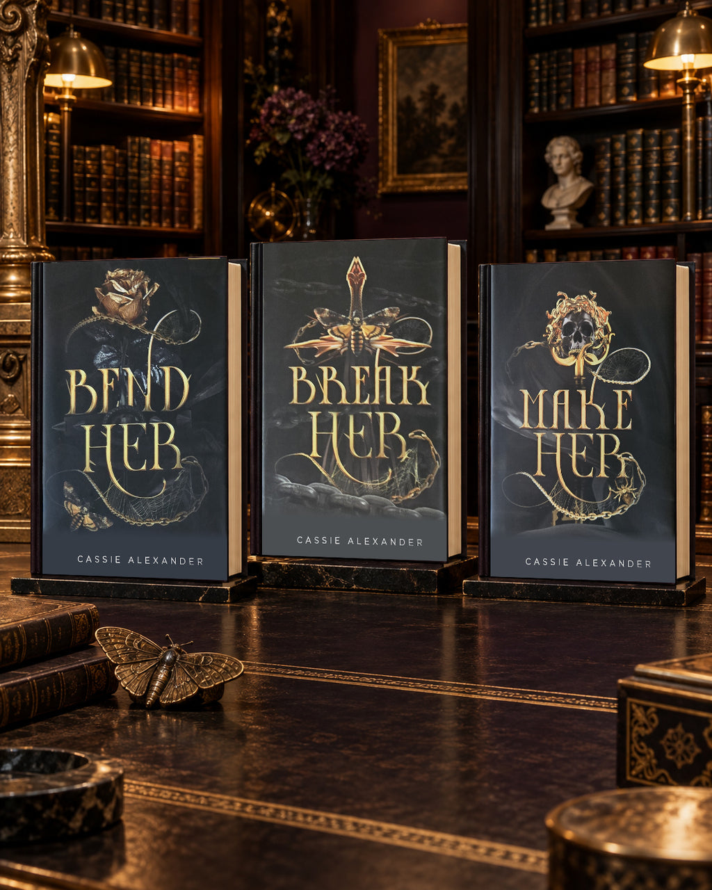 Bend Her, Break Her, and Make Her dust-jacket hardcovers displayed together in a warm gilded library