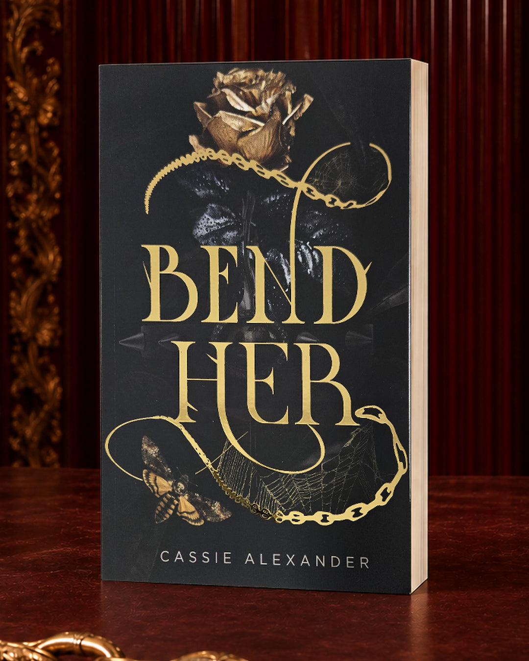 Bend Her black-and-gold foil paperback in an oxblood editorial setting