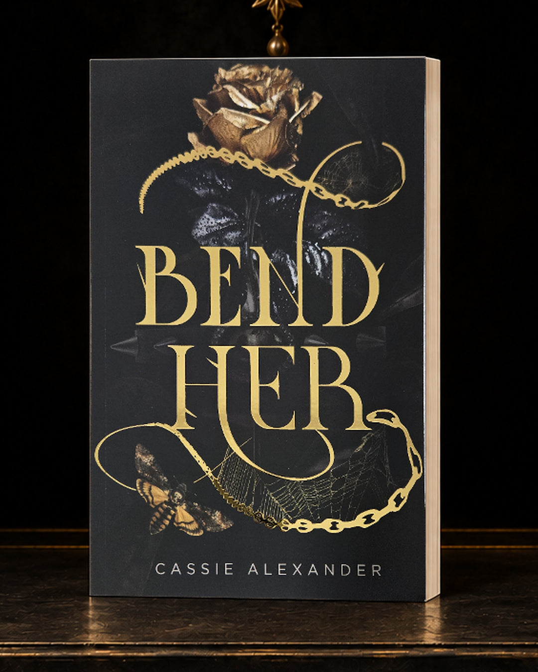 Bend Her black-and-gold foil paperback in a dark gilded vault