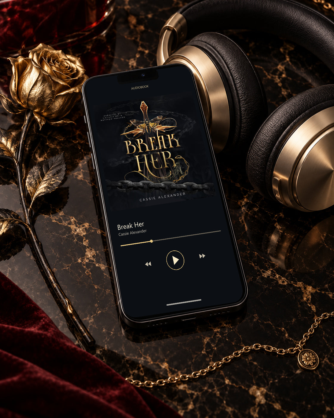 Break Her audiobook on a phone beside black-and-gold headphones, a gold rose, and burgundy velvet
