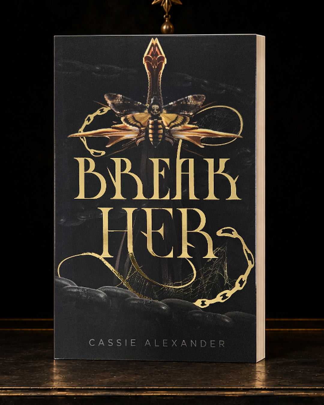 Break Her black-and-gold foil paperback in a dark gilded vault
