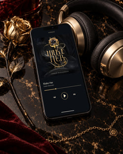 Make Her audiobook on a phone beside black-and-gold headphones, a gold rose, and burgundy velvet