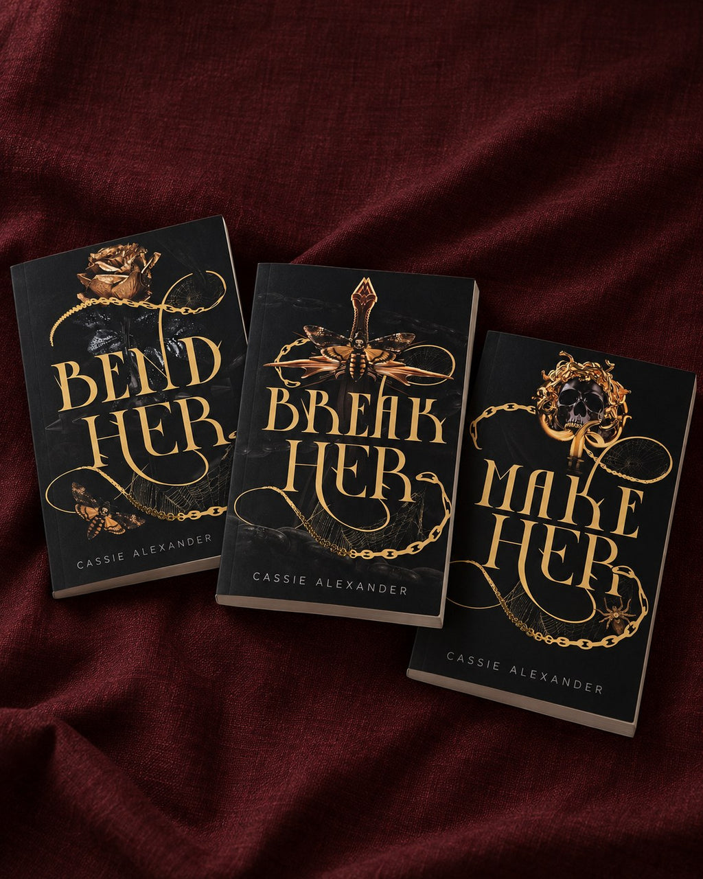 Bend Her, Break Her and Make Her — three complete black-and-gold foil paperbacks together on burgundy velvet
